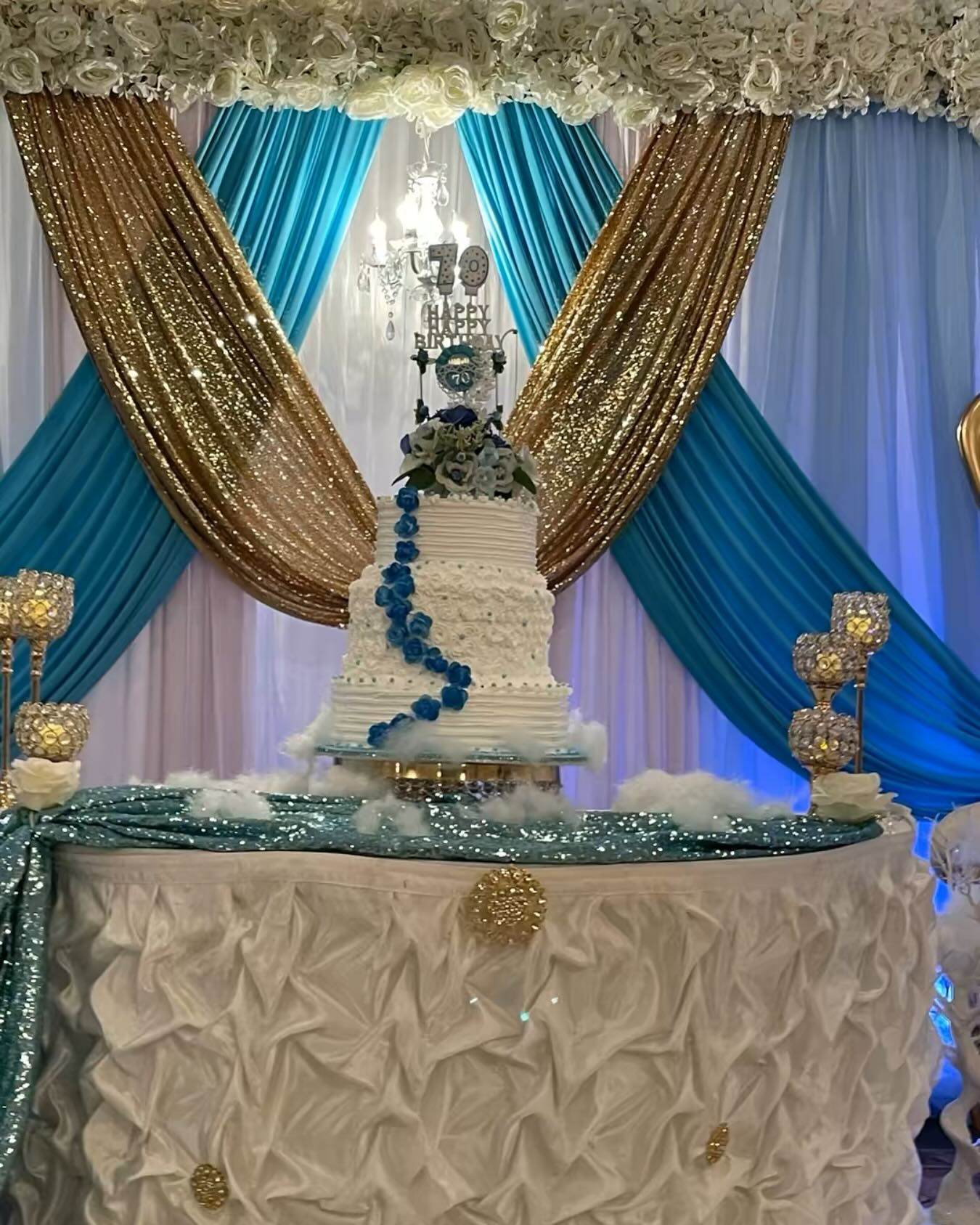 70th birthday cake table with teal and gold sequin draped backdrop and ruffled table skirt
