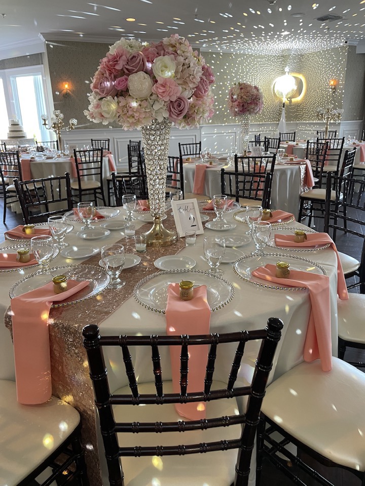 Wedding reception ballroom with tall pink and white floral centerpieces and peach napkins