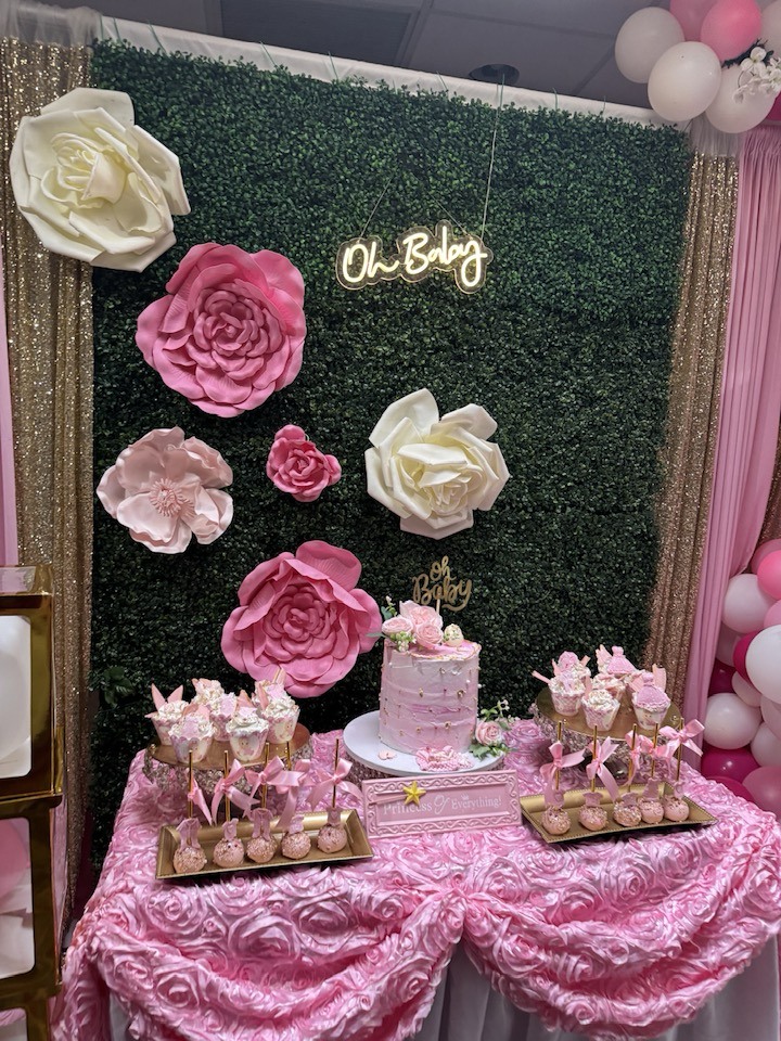 Pink and white baby shower dessert table with greenery wall, paper flowers, and Oh Baby neon sign