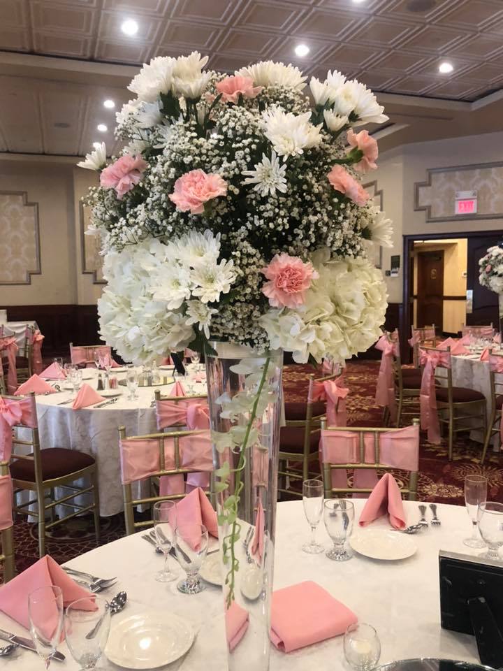 Shower reception ballroom with tall white and pink floral centerpiece in a glass vase and blush napkins
